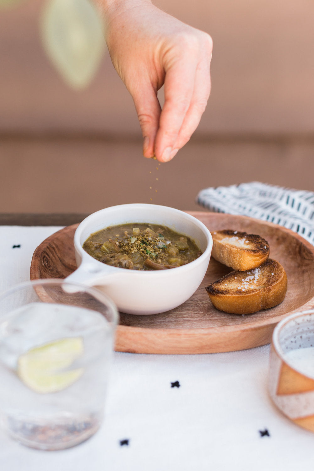 Person sprinkling hatch green chile salt over a bowl of soup